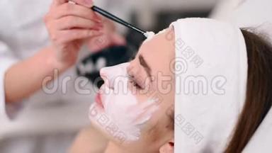 美容专家使用刷子涂抹面膜，使皮肤<strong>水润</strong>健康。 迷人的女人令人放松